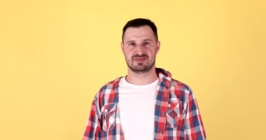 Mutlu genç sakallı adam bağırıyor ve zaferi kutluyor sarı arka planda izole edilmiş.