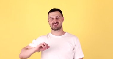 Mutlu bir adamın portresi. El sallayarak selam veriyor. Katı sarı arka planda izole edilmiş..