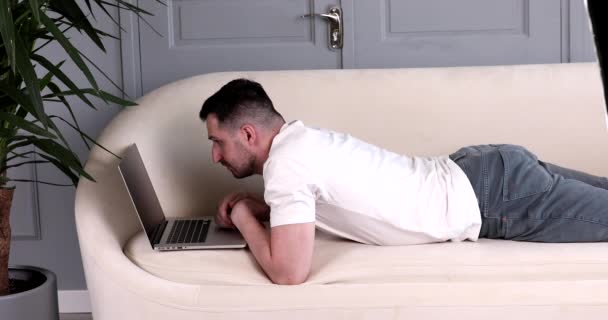 Бородатий Красивий Молодий Чоловік Лежить Дивані Використовує Ноутбук Вдома — стокове відео