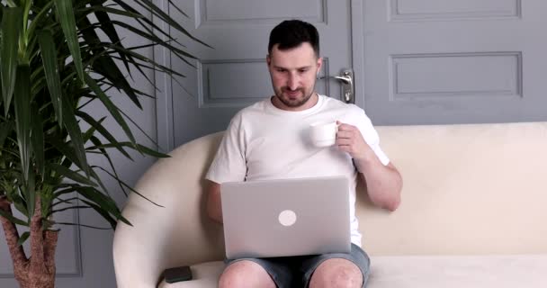 Sakallı Yakışıklı Genç Adam Kanepede Oturuyor Evde Dizüstü Bilgisayar Kullanıyor — Stok video