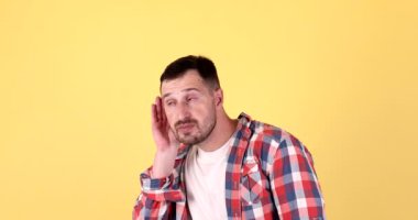 Genç, sakallı, beyaz, sırları dinleyen, sarı arka planda izole bir adam. 