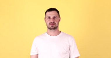 Gülümseyen genç adam, kendine güveniyor. Sarı arka planı imzala..