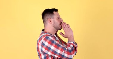 Sakallı adamın portresi, dua ediyor, yalvarıyor, el ele tutuşuyor, umut dolu bir yüz ifadesiyle sarı arka planda izole edilmiş..