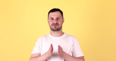 Yakışıklı adam, sarı arka planda boş elle bir şey sunuyor..