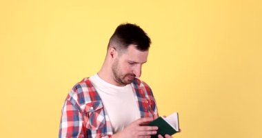 İzole edilmiş sarı arkaplan üzerinde kitap okuyan adam.