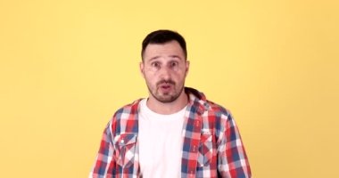 Korkmuş genç adam yüzünü kapatıyor. Avuç içleri sarı arka planda.