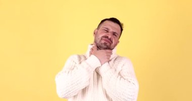 Boğaz ağrısı. Yakışıklı bir adam boynunu tutuyor, boğazında korkunç bir ağrı, sağlık sigortası ve sarı arka planda tıbbi konsept var..