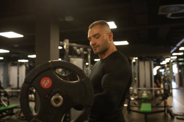Kaslı adam ile halter, pazı egzersizleri yapıyor spor salonunda egzersiz. 