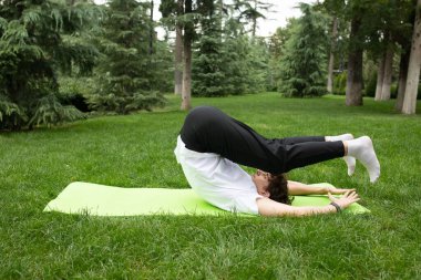 Bahçede yoga minderiyle egzersiz yapan bir adam. Sağlık için egzersiz. Yoga. 