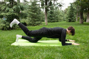 Bahçede yoga minderiyle egzersiz yapan bir adam. Sağlık için egzersiz. Yoga. 