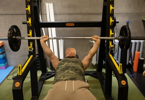 Man during bench press exercise with barbell in gym.