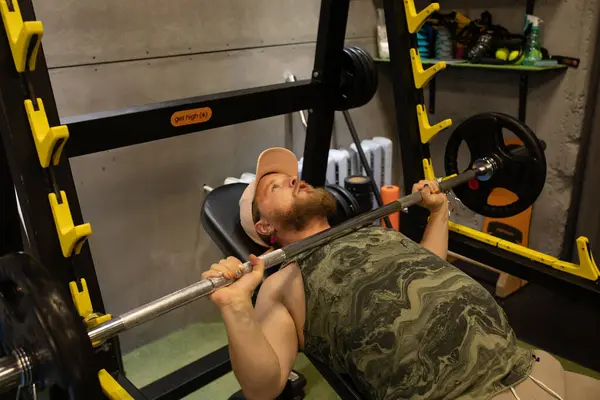 Man during bench press exercise with barbell in gym.