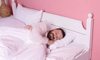 Sakallı yakışıklı genç adam evde yatakta uzanıyor ve uyuyor..