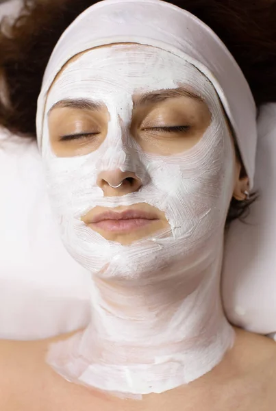 Face mask, spa beauty treatment. Woman applying facial clay mask at spa salon, skincare.