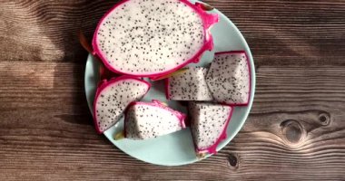 Dilimlenmiş ejderha meyvesinin yakın plan görüntüsü, ahşap masa arkasında tabakta egzotik ejderha meyvesi. Pitahaya.      