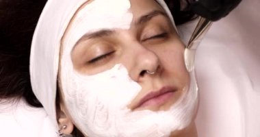 Genç güzel bir kadın güzellik salonunda beyaz yüz maskesi takıyor..   