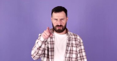 Kızgın sakallı genç adam bana geldi ve mor arka plandaki kameraya baktı.