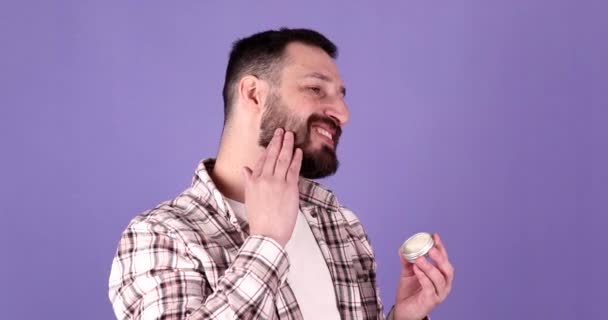 Красивий Бородатий Чоловік Тримає Бородатий Бальзам Фіолетовому Фоні — стокове відео