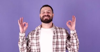 Sakin ol, rahatla, iç denge. Mudra jestli genç beyaz adam, gözleri kapalı, mor arka plan üzerinde meditasyon yapıyor..      