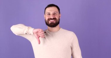 Genç sakallı adam, mor arka plan üzerinde olumsuz jest yapıyor..