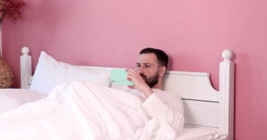 Sakallı adam telefonda video seyrediyor ve kendinden memnun, ergenlik yaşı, hormonal değişim..