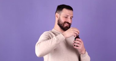 Güzellik, cilt bakımı ve kozmetik ürünleri için mor bir stüdyo arka planında insan, yüz ve temel yağ. Sakal için yağ.