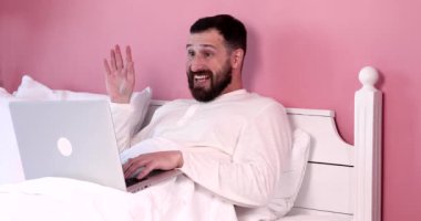 Genç sakallı adam yatak odasında video görüşmesi yapıyor..