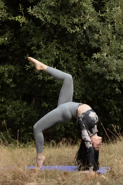 Antrenman için ormanda yoga yapan genç bir kadının portresi. Zindelik ve sağlıklı yaşam tarzı kavramı .