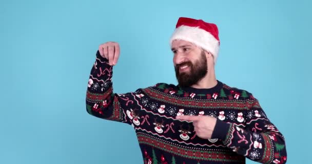 Happy Young Bearded Man Christmas Sweater Santa Hat Pointing Something — Stock Video