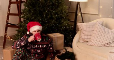 Genç sakallı adam evde Noel ağacının yanında kahve içiyor. Xmas evde..     