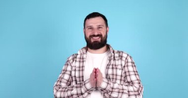 Mavi arka planda izole edilmiş, gülümseyen sakallı genç bir adamın portresi..