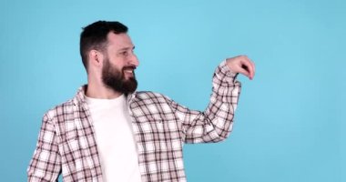 Mavi arka planda izole edilmiş, gülümseyen sakallı genç bir adamın portresi..