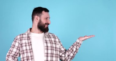 Mavi arka planda izole edilmiş, gülümseyen sakallı genç bir adamın portresi..