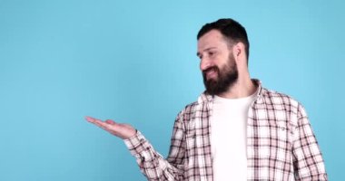 Mavi arka planda izole edilmiş, gülümseyen sakallı genç bir adamın portresi..