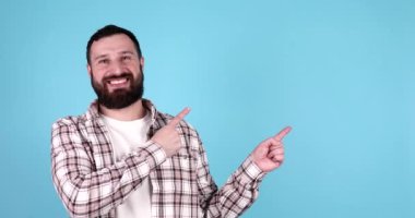 Mavi arka planı gösteren sıradan giysili, gülümseyen, sakallı, genç, çekici bir adam.. 