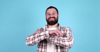 Mavi arka planda duran ve gülümseyen yakışıklı sakallı genç adamın portresi.