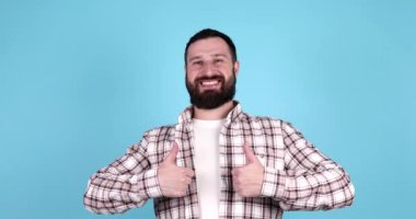 Mavi arka planda izole edilmiş, gülümseyen sakallı genç bir adamın portresi..