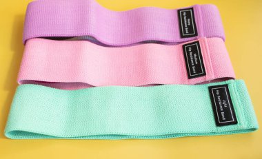 Sarı arka planda fitness için renkli kalça direnci bantları. spor konsepti.      