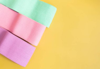 Sarı arka planda fitness için renkli kalça direnci bantları. spor konsepti.      