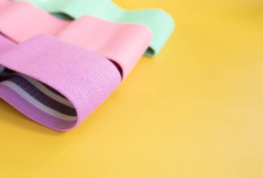 Sarı arka planda fitness için renkli kalça direnci bantları. spor konsepti.      