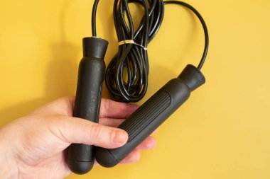 Sarı arka planda siyah saplı ip tutan kişinin yakın görüntüsü.    