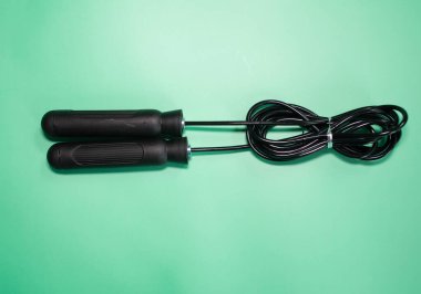 Yeşil arkaplanda siyah saplı ip atlanıyor.