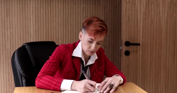 Όμορφη Μεσήλικη Επιχειρηματίας Κόκκινο Κοστούμι Γράφοντας Στο Σημειωματάριο Στο Γραφείο — Αρχείο Βίντεο