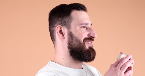 Красивый Бородатый Мужчина Представляет Бальзам Бороды Бежевом Фоне — стоковое видео