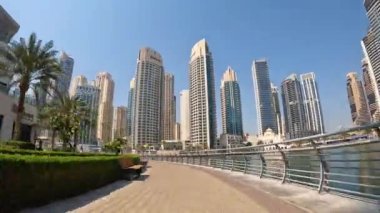 Dubai, BAE, 30 Mart 2024. Arka planda büyük bir su kütlesi olan bir şehir caddesi. Binalar yüksek ve gökyüzü temiz.