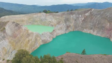 Endonezya 'da. Flores 'teki Kelimutu volkan krateri. İki büyük su kütlesi, yeşil ve mavi. Manzara sakin ve huzurlu, su çevreyi yansıtıyor..             