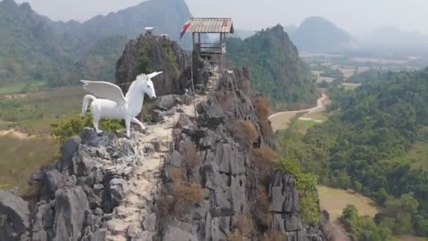 ヴァング ヴィエン ラオス 2023年12月25日 岩山に白い馬の像が置かれている 彫像はペガサスで それは木に囲まれています — ストック動画