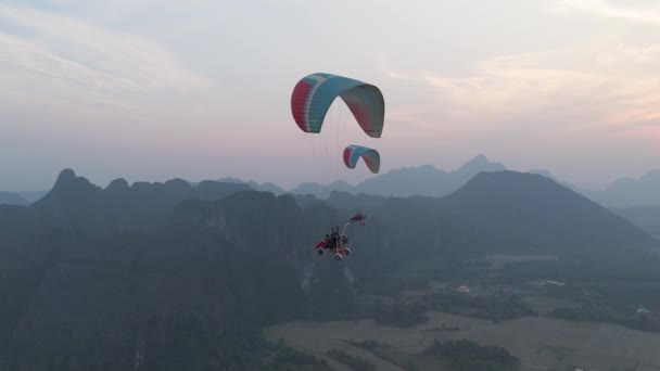 ヴァンヴィエン ラオス 11月2023日 下の都市と美しい自然の上にパラグライダーを飛んでいる人々 — ストック動画