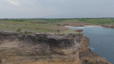 Lombok, Endonezya. Okyanusa bakan bir uçurumun kenarında duran bir adam. Sahne sakin ve huzurlu, manzaranın ve dalgaların altında.           