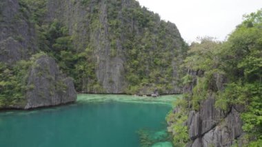El Nido, Palawan, Filipinler 'deki muhteşem Büyük Göl manzarası. Kayalık bir kıyıya yakın okyanusta yüzen tekneler. 